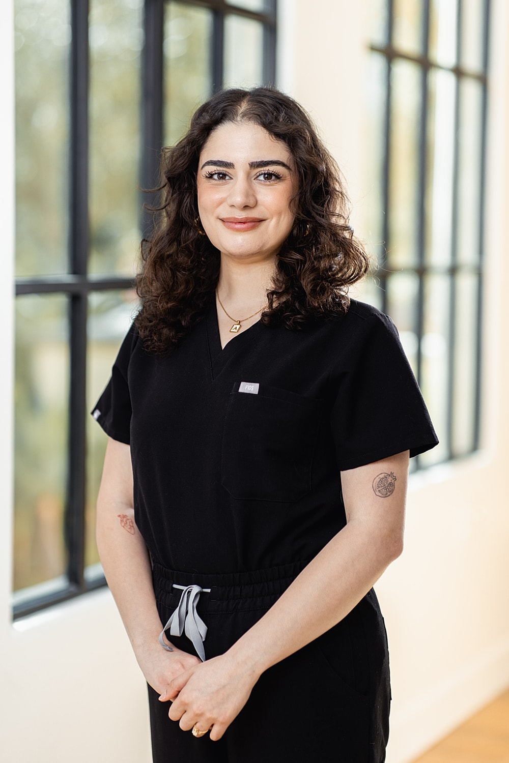 Woman in black scrubs smiling indoors.