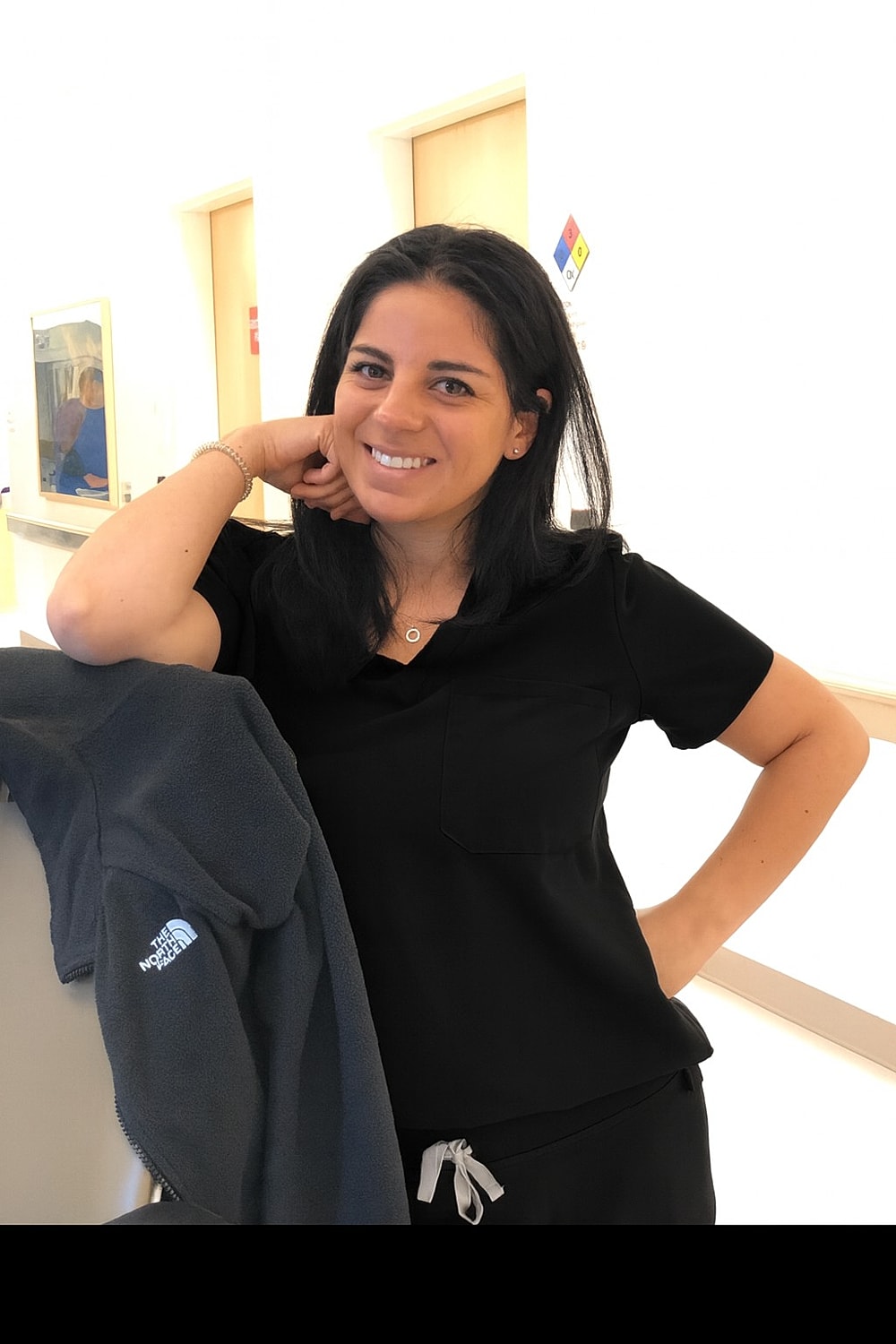 Smiling woman in black outfit, posing confidently.