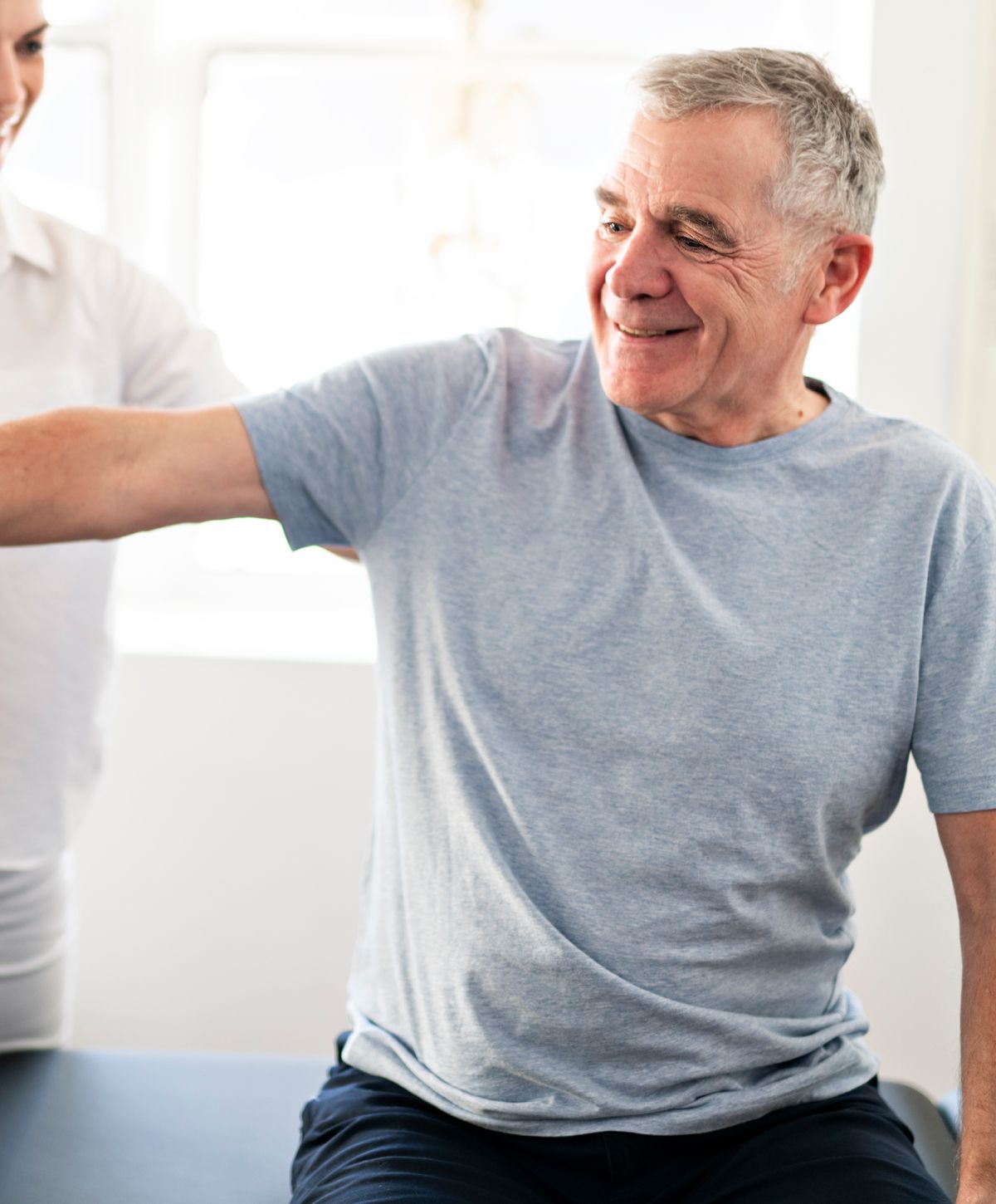 Elderly man receiving physical therapy assistance.
