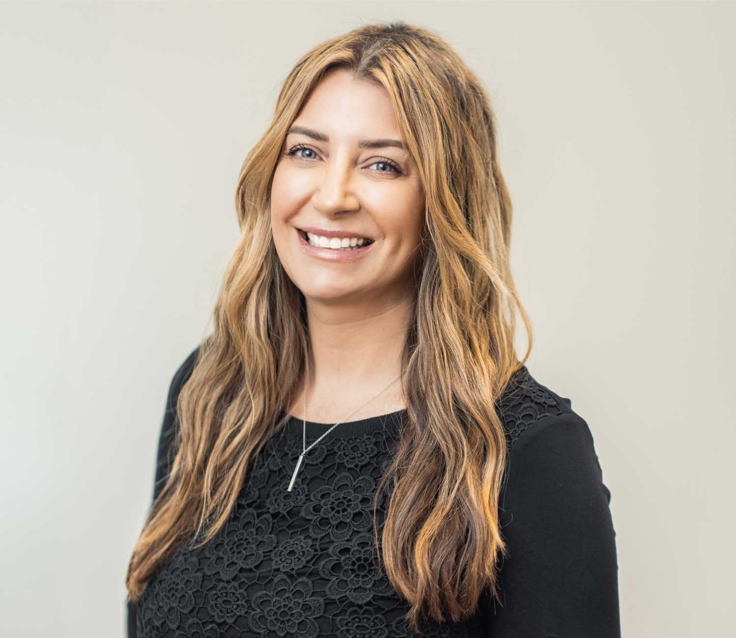 Smiling woman with long hair in black dress.