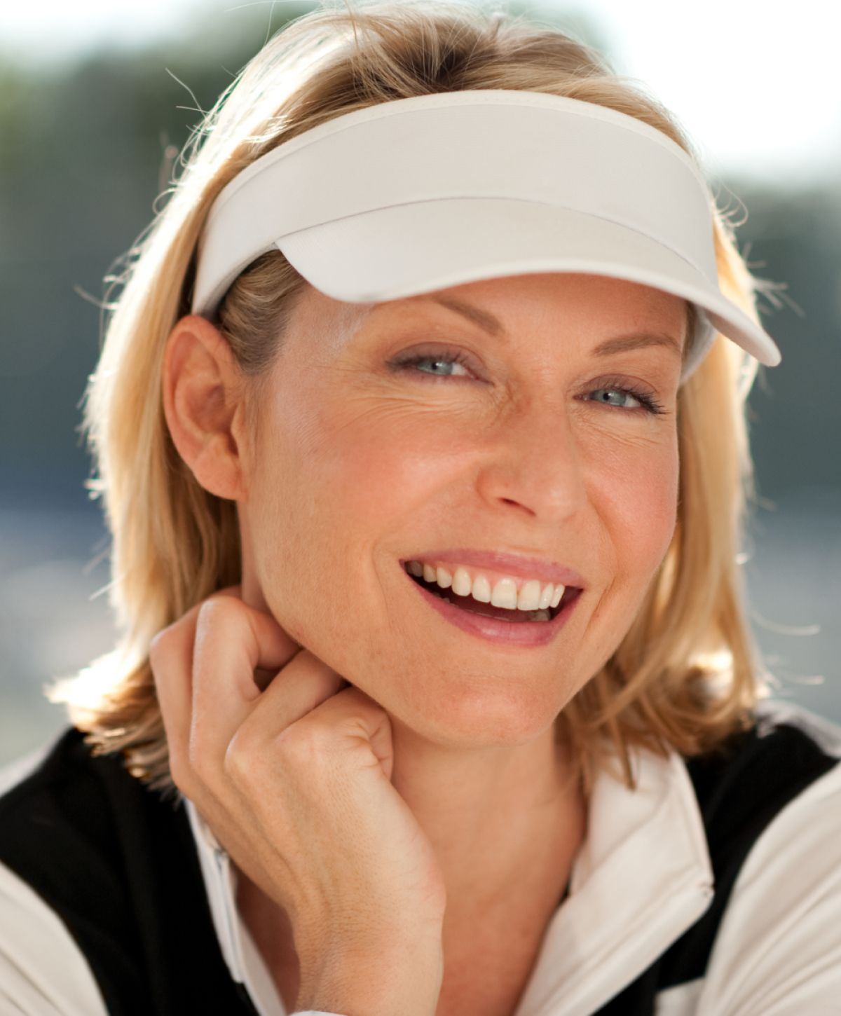Smiling woman wearing a visor, relaxed pose.