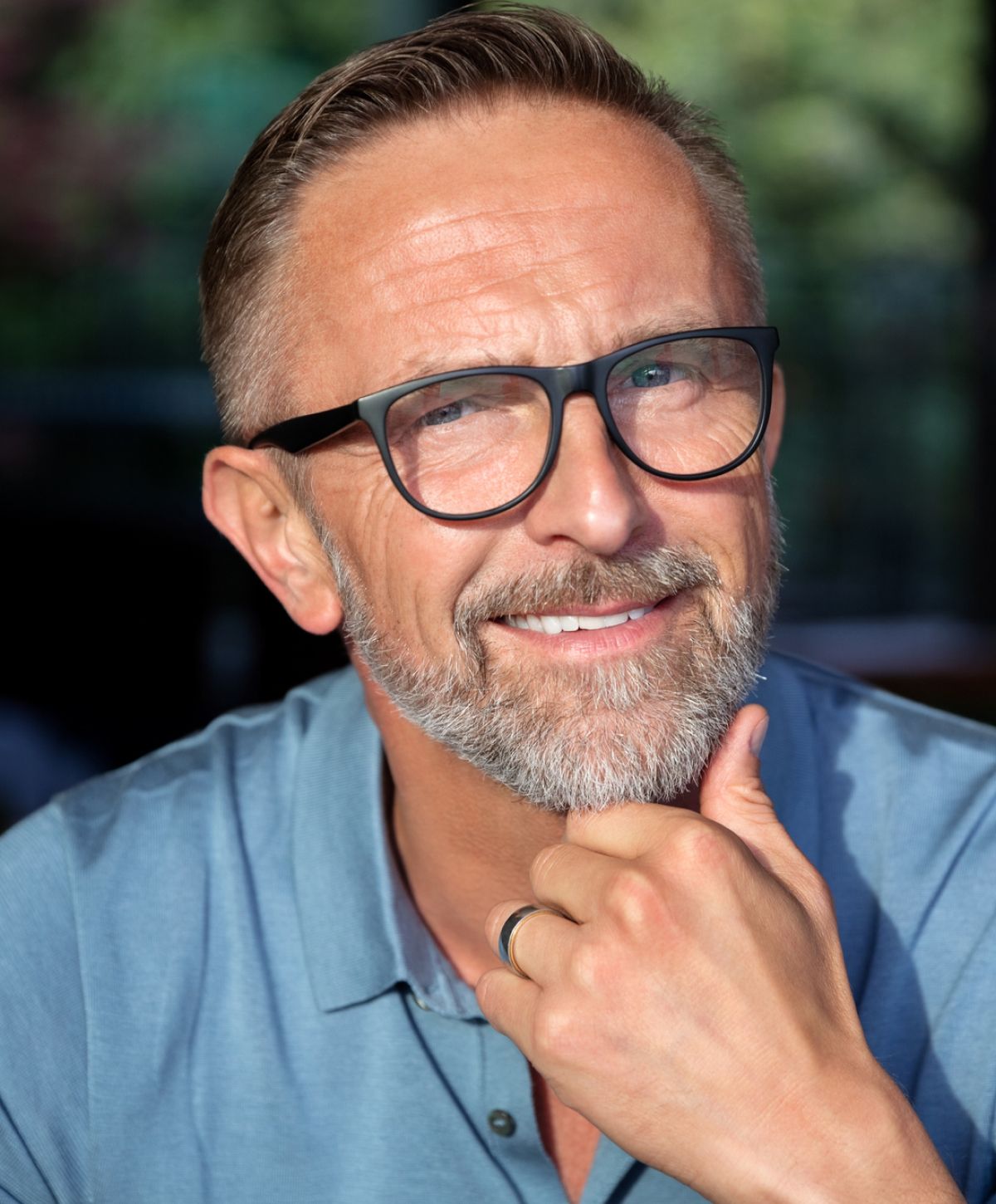 Smiling man with glasses and beard, thoughtful expression.
