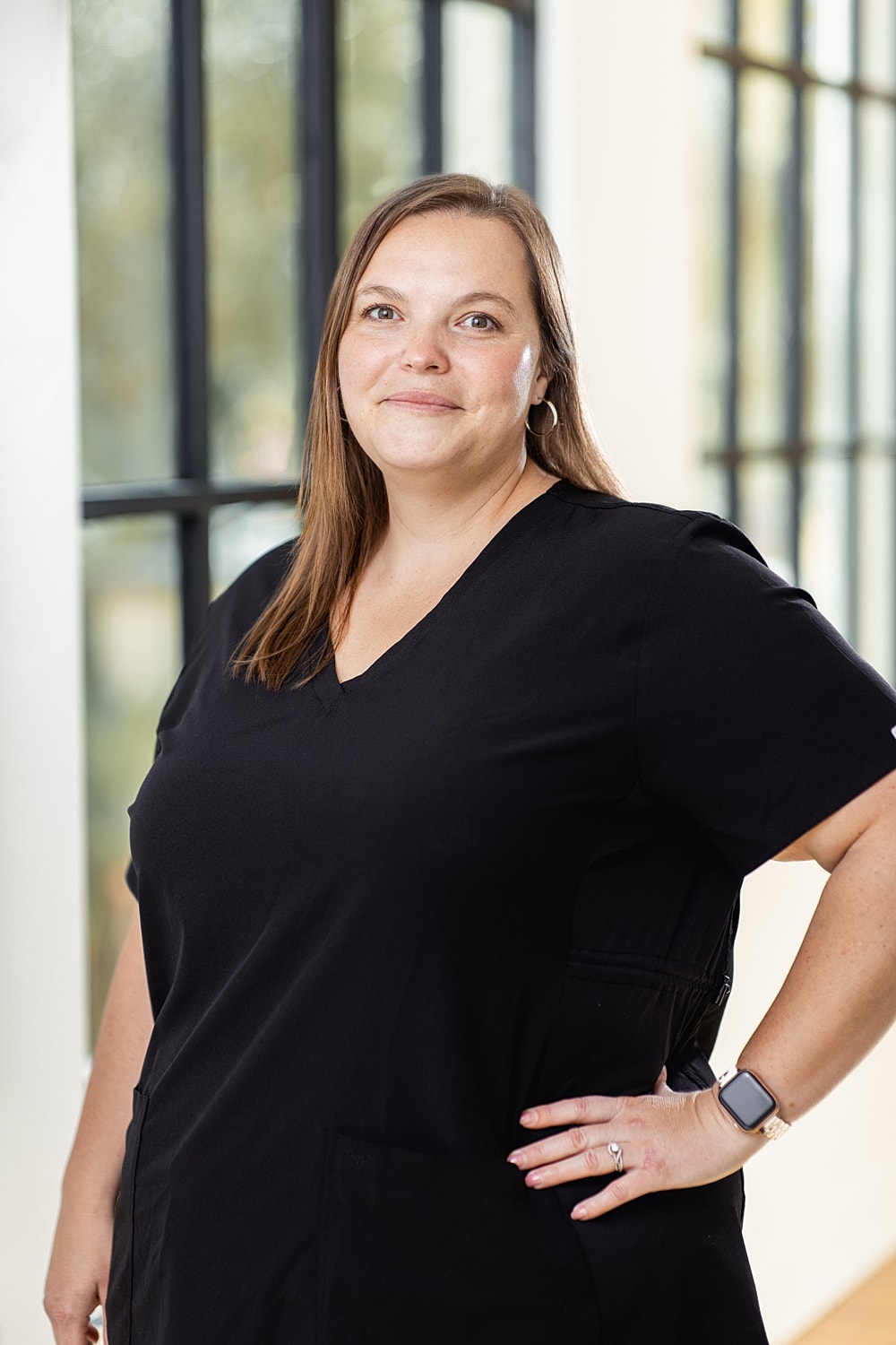Smiling woman in black scrubs, indoors.