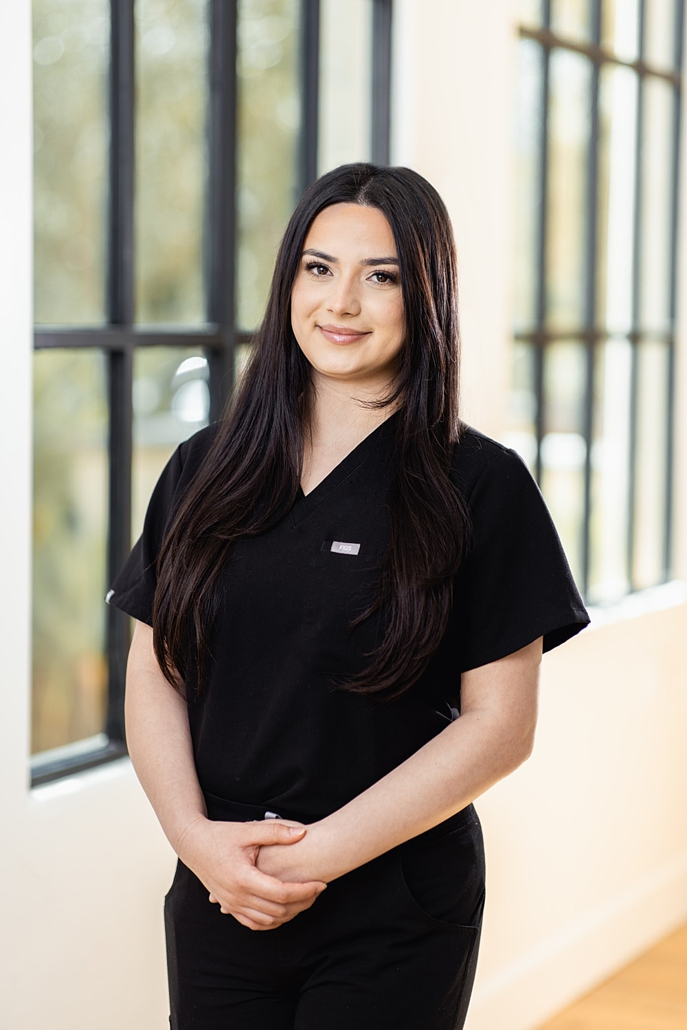 Professional woman in black scrub attire, smiling.