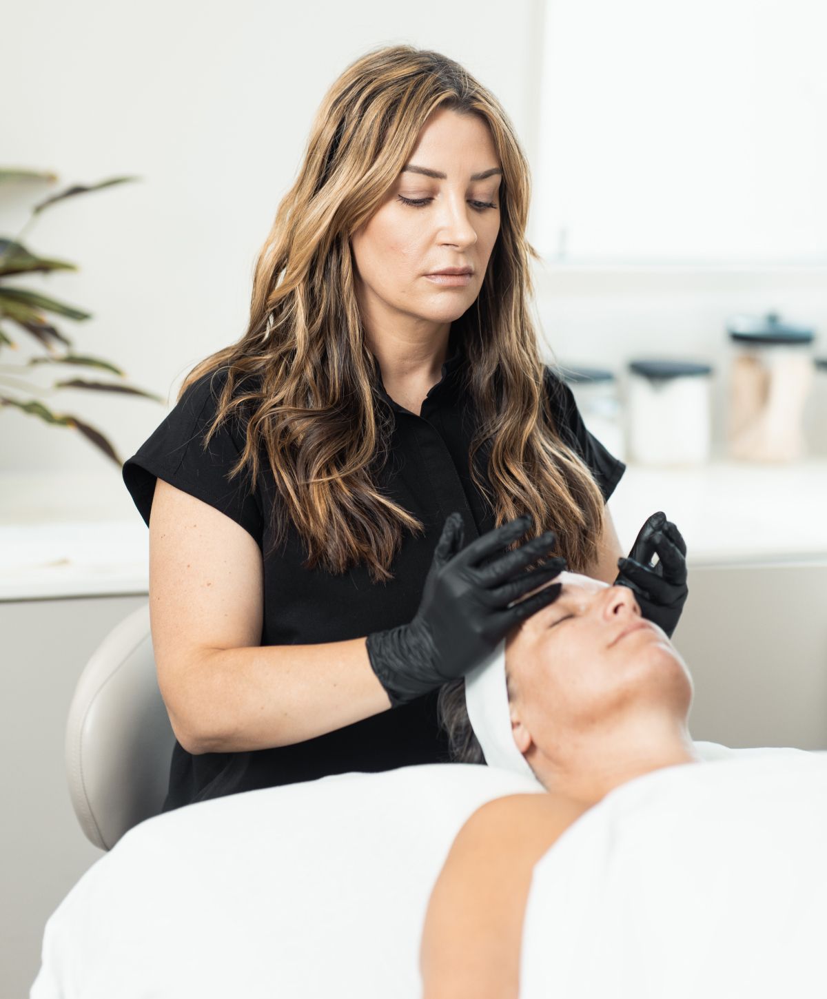 Esthetician performing facial treatment on client.