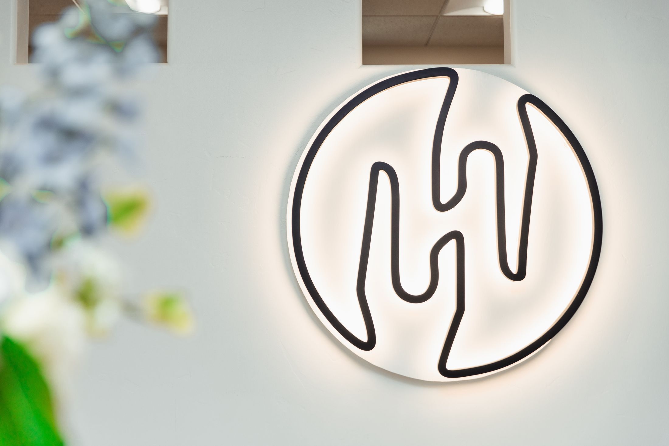 Stylized logo on wall with soft lighting.