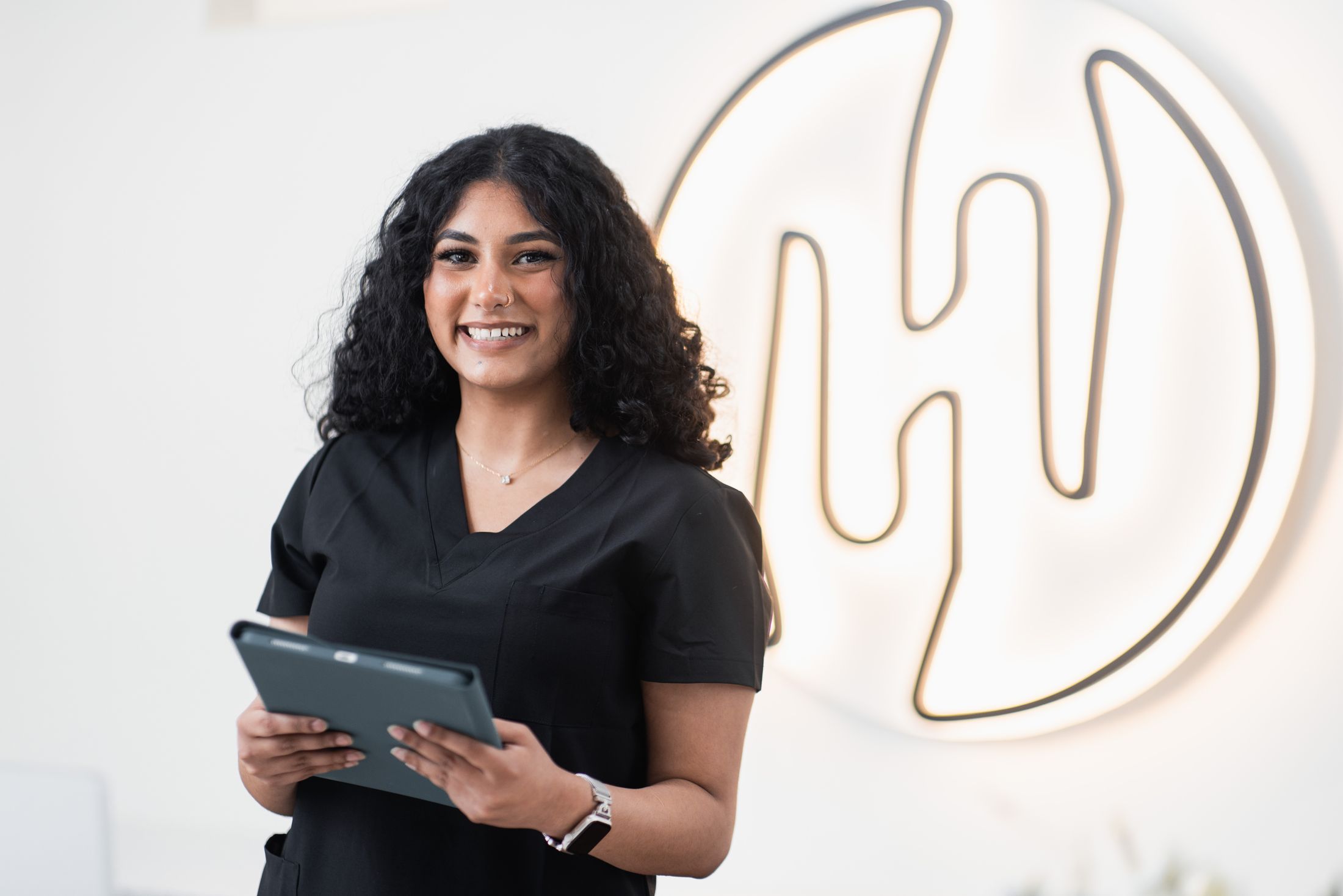 Smiling woman holding tablet in modern setting.