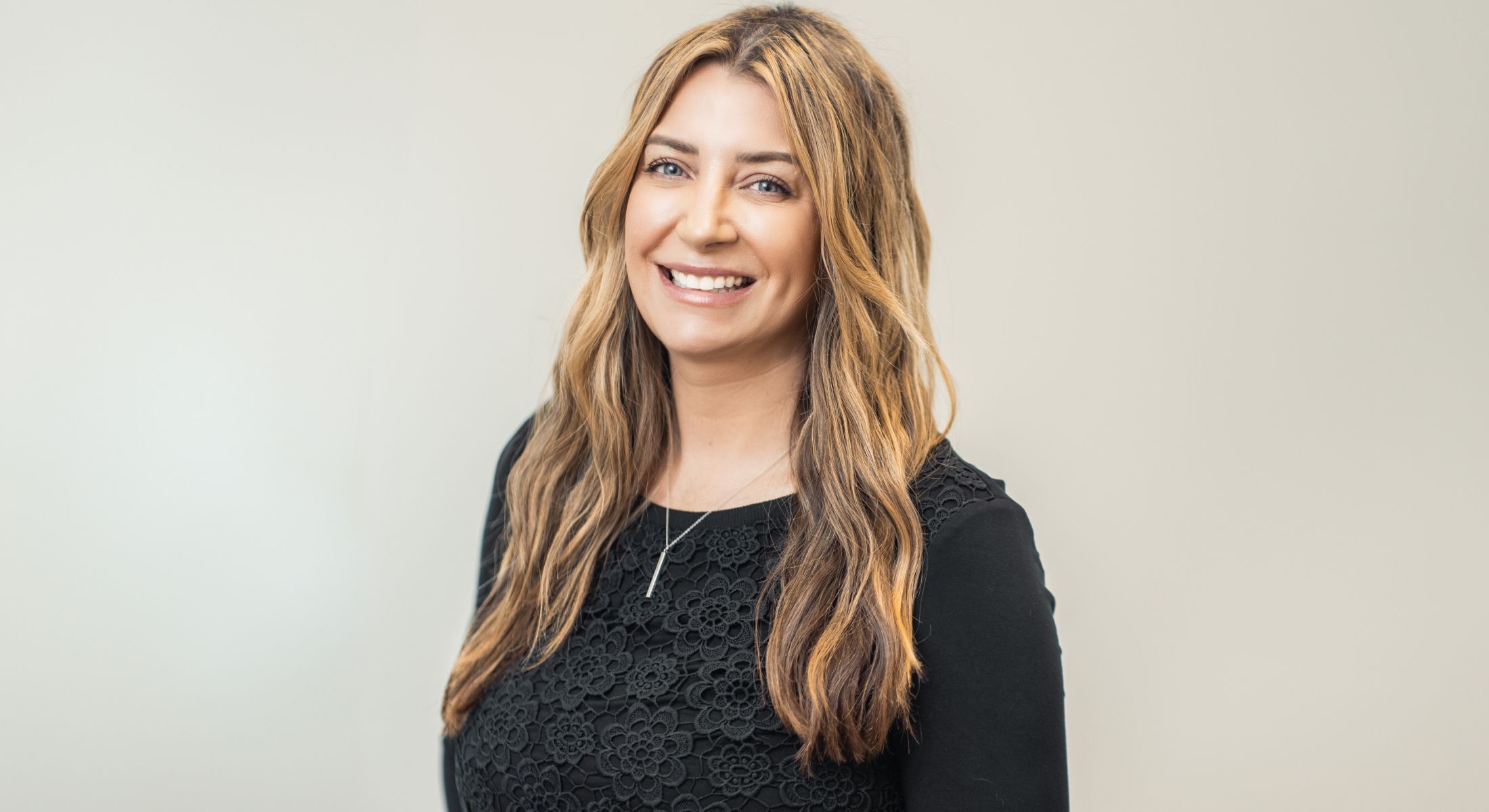 Smiling woman with long hair in a black top.
