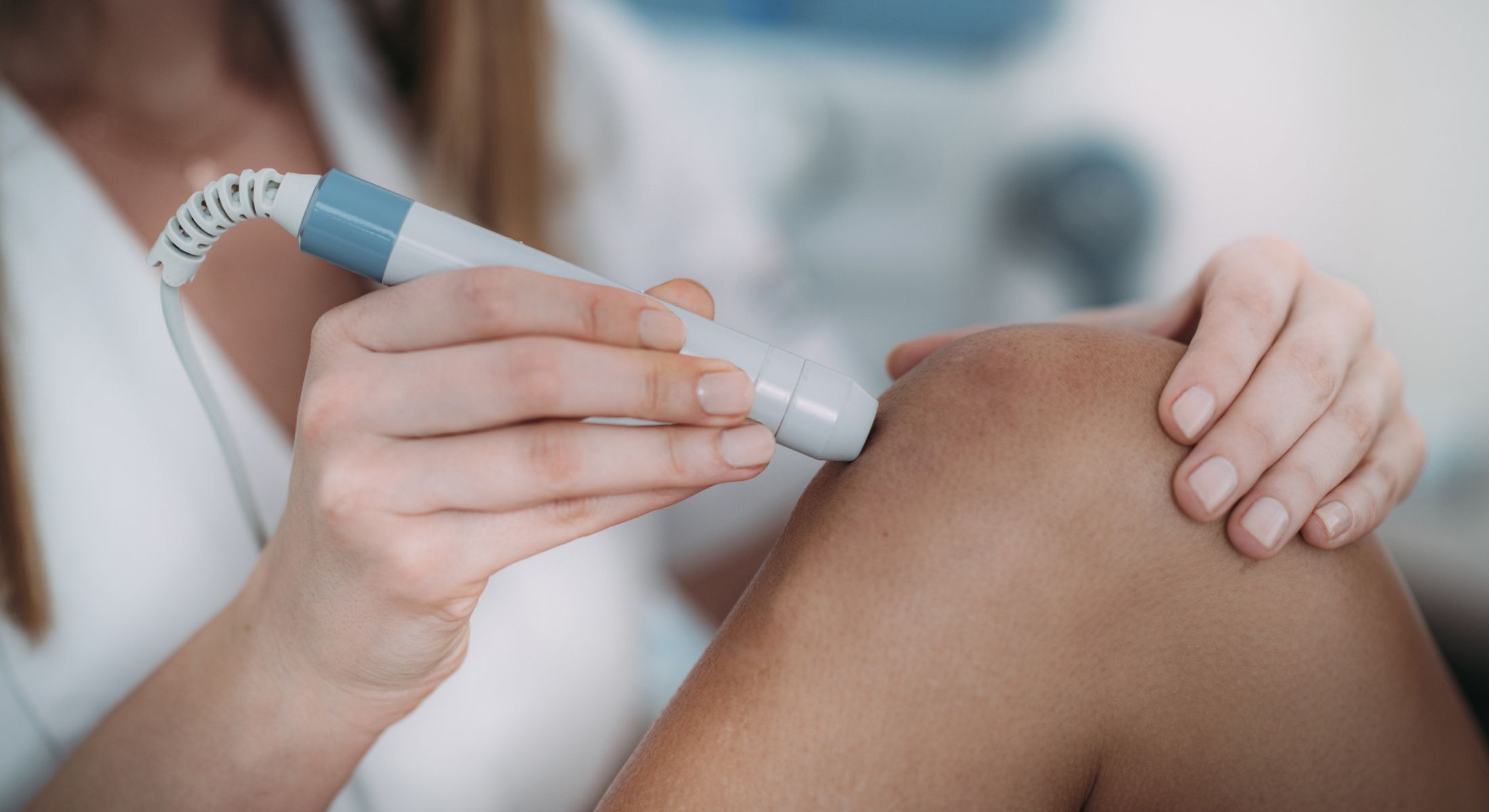 Woman treating knee with medical device.